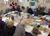 People drawing and painting at tables in a NETA art class
